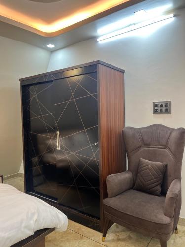 a bedroom with a chair and a large entertainment center at Lawn Side Manor in Jhājra