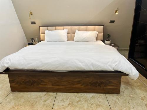 a large bed with white sheets and pillows on it at Lawn Side Manor in Jhājra