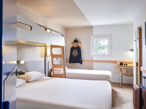 a hotel room with two beds and a mirror at ibis budget Versailles Chateau Saint cyr l'Ecole in Saint-Cyr-lʼÉcole