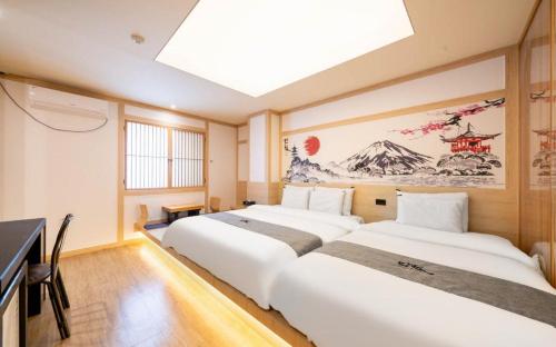 two beds in a room with a painting on the wall at Daeheung Manwol Hotel in Daejeon