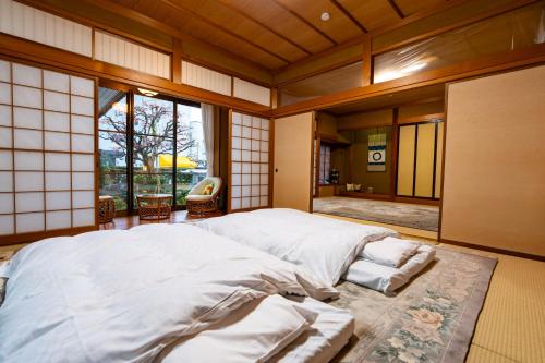 a bedroom with a large bed in a room with windows at 勝山恐竜博物館まで車で10分最大10名様ふとん屋の宿 悦 in Katsuyama