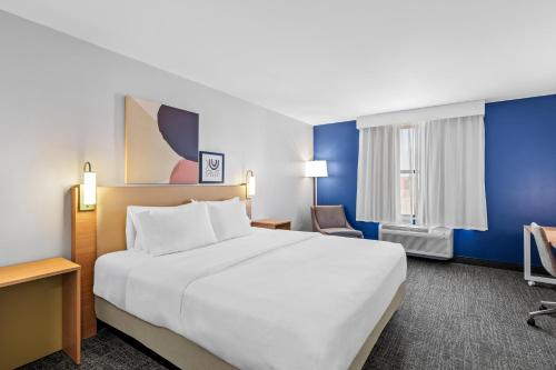 a hotel room with a large bed and a chair at Spark by Hilton Shawnee in Shawnee