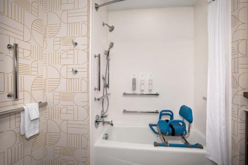 a bathroom with a blue chair next to a bath tub at Home2 Suites By Hilton Big Spring in Big Spring