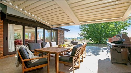 a patio with a wooden pergola and a table and chairs at Warrington Park in Berrima