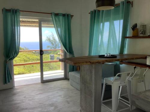 a dining room with a table and a large window at Studio Ti Lakaz lao in Petit Brûlé