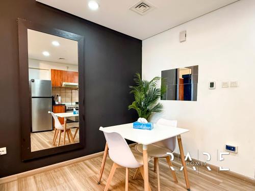 a dining room with a white table and chairs at Rare Holiday Homes - Crescent Tower - IMPZ - Dubai Production City - R704 in Dubai