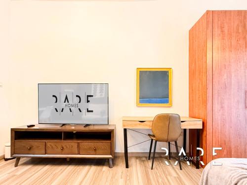 a bedroom with a desk and a chair and a bed at Rare Holiday Homes - Crescent Tower - IMPZ - Dubai Production City - R704 in Dubai