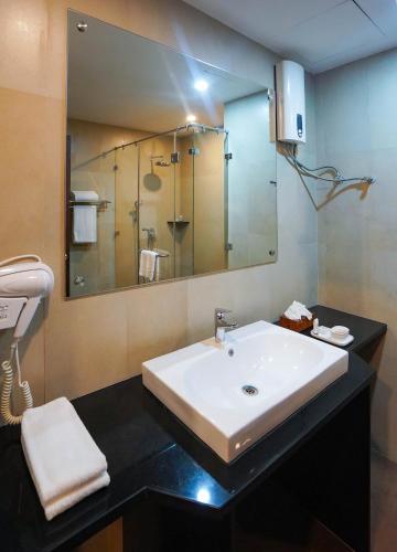 a bathroom with a sink and a large mirror at CityHotel, Thimphu in Thimphu