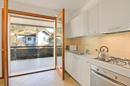 a kitchen with white cabinets and a view of a balcony at Magnolia: Laveno Centre 2BR with Terrace - Happy Rentals in Laveno-Mombello