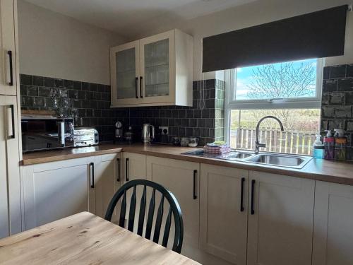 a kitchen with a table and a sink and a window at The Old Garage in Rural Northumberland in Edlingham