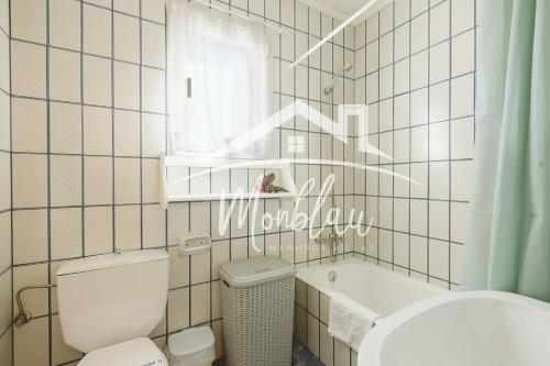 a bathroom with a toilet and a tub and a window at Sa Torreta 4 in Cala Blanca