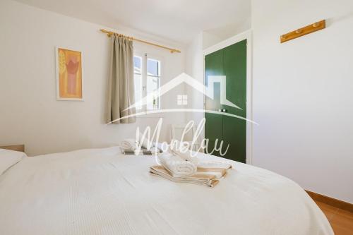 a bedroom with a white bed with towels on it at Sa Torreta 3 in Cala Blanca