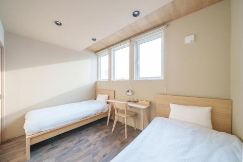two beds in a room with a desk and two windows at ZABOCON Honcho Terrace in Sapporo