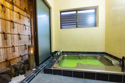 a green bath tub in a bathroom with a window at 勝山恐竜博物館まで車で10分最大10名様ふとん屋の宿 悦 in Katsuyama