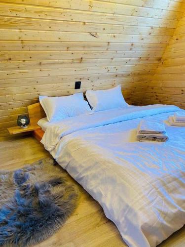 a large bed in a room with a wooden wall at Cabana Muncelus in Lupşa
