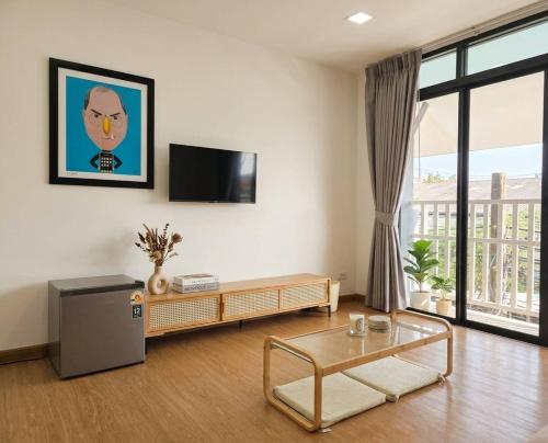 a living room with a tv and a table at Hugg daily airport in Ban Khlong Thewa