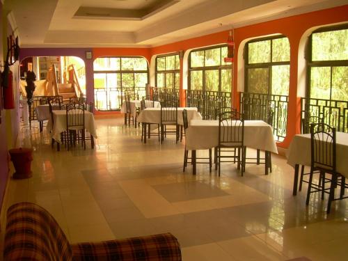 a dining room with tables and chairs and windows at Kakakuona Resort in Lushoto