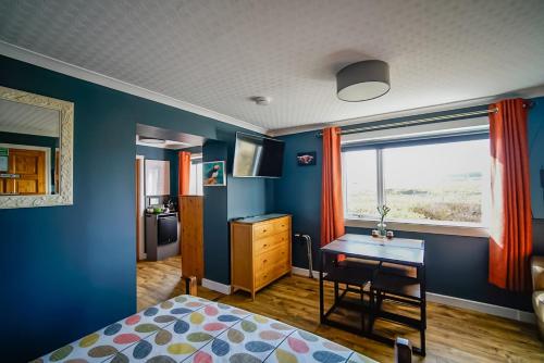 a bedroom with blue walls and a desk and a window at Burnside Cottage in Wick
