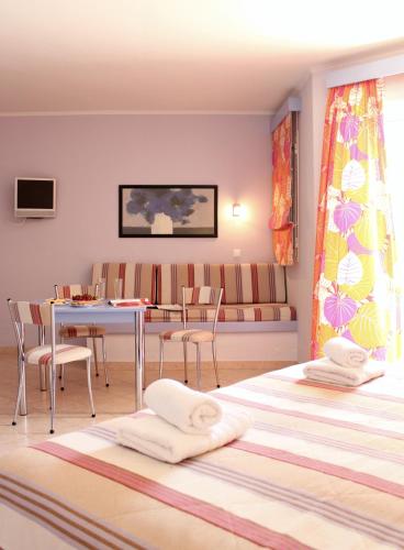 a room with a couch and a table with chairs at Amaryllis Hotel Apartments in Tolo