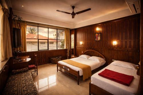 a bedroom with two beds and a window at Dolphin Residency in Thekkady