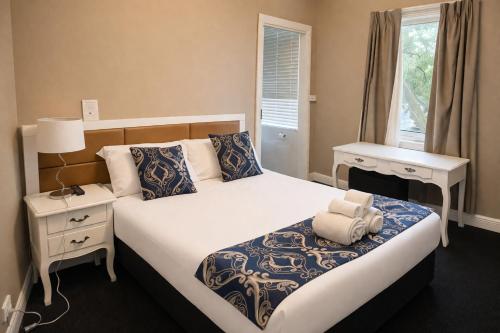 a bedroom with a large bed with a night stand and a window at Lily Sands Inn in Melbourne