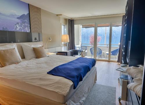 a bedroom with a large bed with a blue blanket on it at Seehotel Riviera at Lake Lucerne in Gersau
