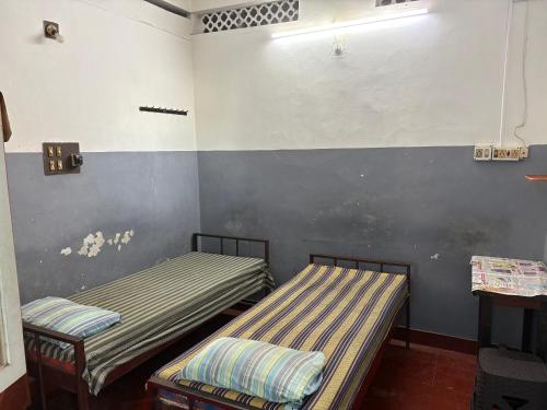 two twin beds in a room with a wall withacers at Star Hostel in Kannur