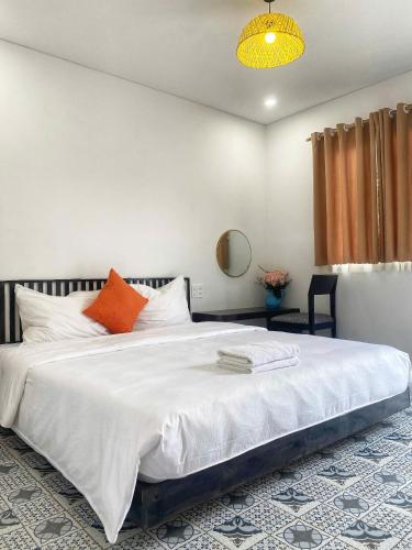 a bedroom with a large white bed with an orange pillow at SAKURA Retreat in Mộc Châu