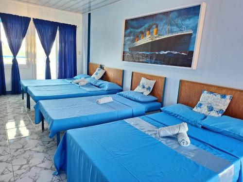 a room with three beds with blue sheets at Hotel Tagudan Kubo Corporation in Tagudin