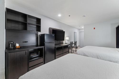 a hotel room with two beds and a desk with a television at Baymont by Wyndham San Antonio Downtown in San Antonio