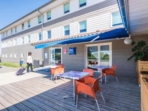 a building with tables and chairs on a deck at ibis budget Amberieu en Bugey/Chateau Gaillard A42 in Château-Gaillard