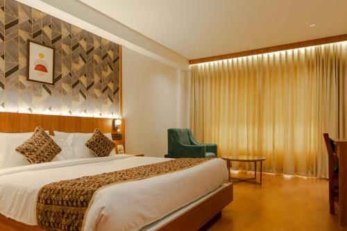 a hotel room with a bed and a chair at Hotel Sky International in Kizhake Chālakudi
