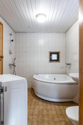 a white bathroom with a tub and a sink at Himos Mökki in Jämsä