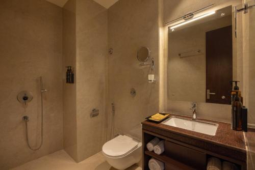 a bathroom with a toilet and a sink and a shower at Clarks Inn Suites Dhanbad in Dhanbād