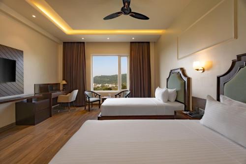 a hotel room with two beds and a desk at Clarks Inn Suites Dhanbad in Dhanbād