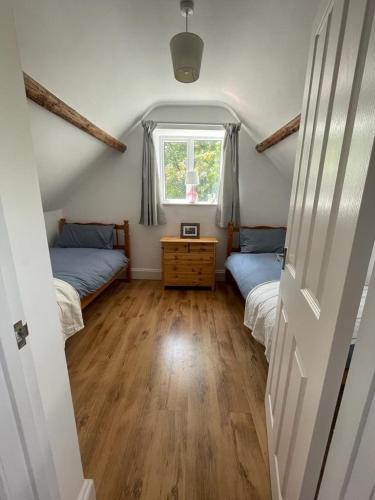 a bedroom with two beds and a window at Copswood Cottage in Stroud