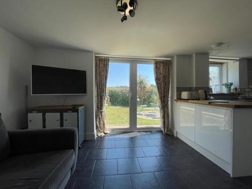 a living room with a couch and a large window at Copswood Cottage in Stroud