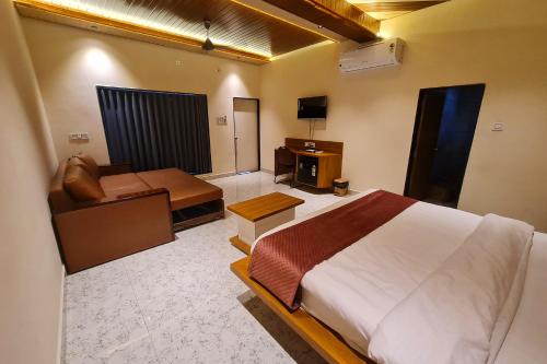 a bedroom with a bed and a couch and a television at The Crystal Woods Resort in Mendarda