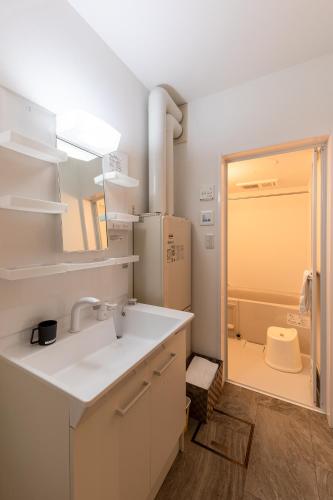 a white bathroom with a sink and a refrigerator at HARUSAKU Omachi in Asahikawa