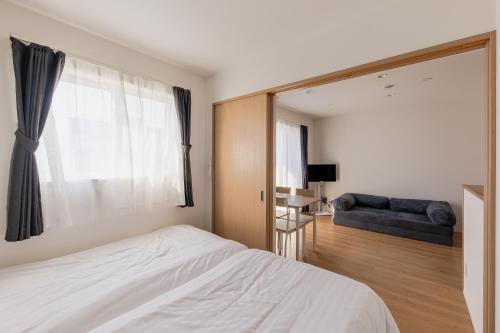 a bedroom with a bed and a couch and a mirror at HARUSAKU Omachi in Asahikawa