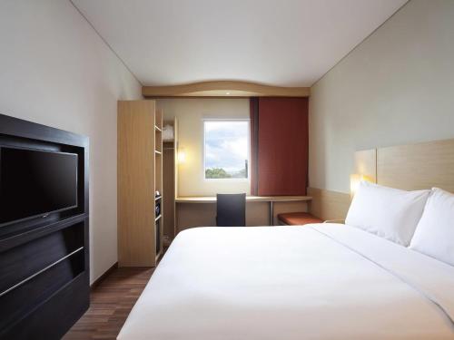 a hotel room with a bed and a flat screen tv at Ibis Makassar City Center in Makassar