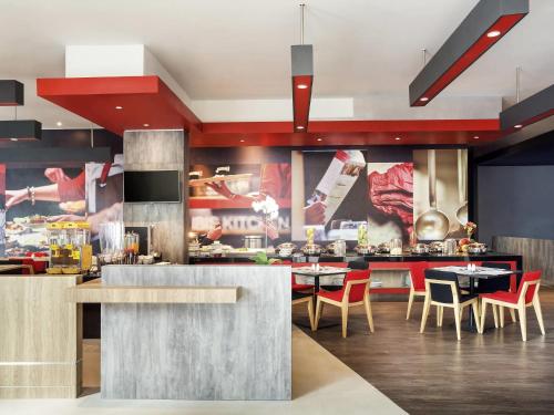 a restaurant with tables and chairs in a kitchen at Ibis Makassar City Center in Makassar