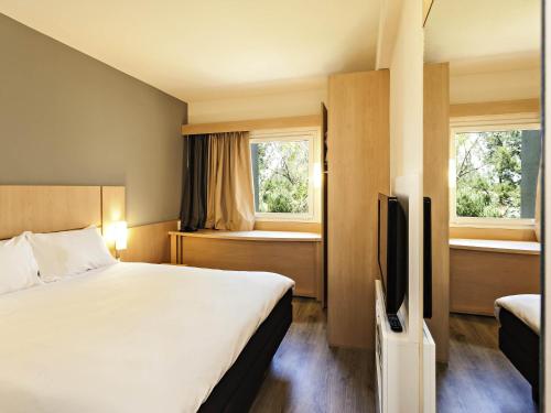 a hotel room with a bed and a flat screen tv at ibis Pilar in Pilar