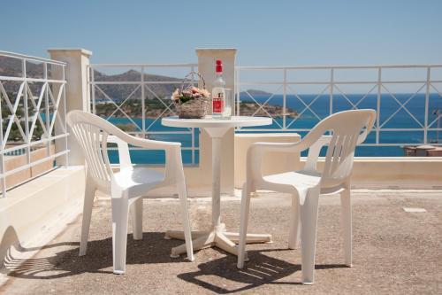two white chairs and a table with a bottle on a balcony at Bellevue Suites in Agios Nikolaos