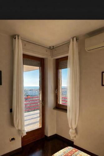 a bedroom with a window with white curtains at Casa Vista Serapo in Gaeta