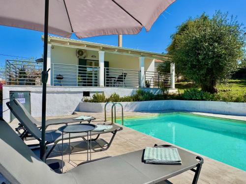 a patio with a table and an umbrella next to a swimming pool at Elea Boutique Villa with private pool by DadoVillas in Acharavi