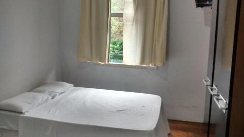 a bed in a room with a window at Pousada Vila Pitanga in Santos