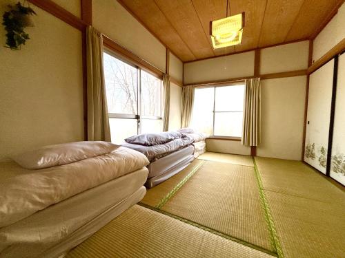 a room with a row of beds in a room with windows at SSK Mountain Base in Tsumagoi
