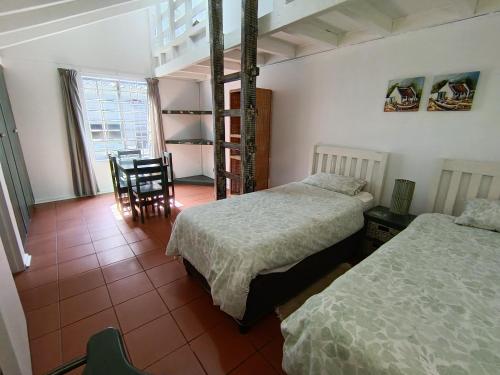 a bedroom with two beds and a table and a chair at Sandkasteel Self-Catering Accommodation in Vosburg