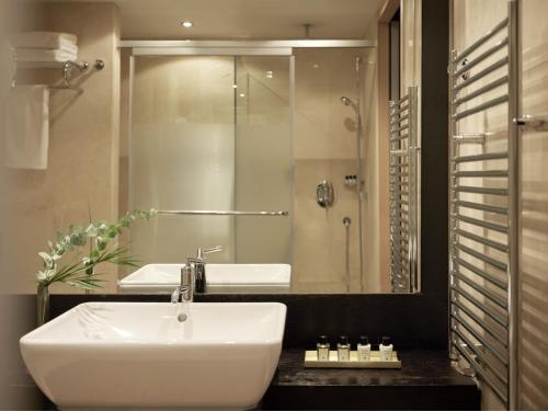 a bathroom with a sink and a large mirror at Daios Luxury Living in Thessaloniki